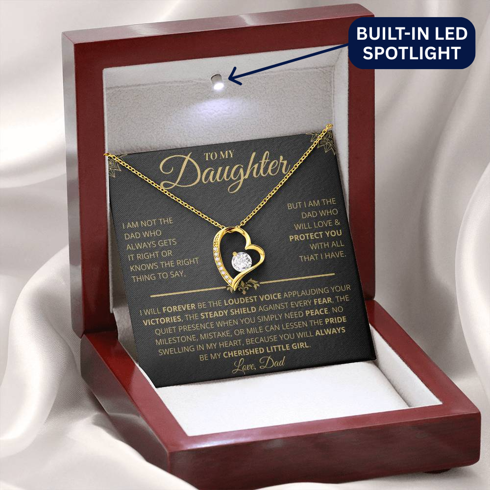 Gold heart-shaped necklace with a message card in a wooden display box on a white background