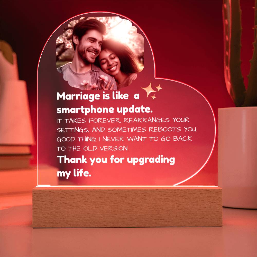 Heart-shaped LED sign with a romantic quote and photo of a couple, placed on a surface.