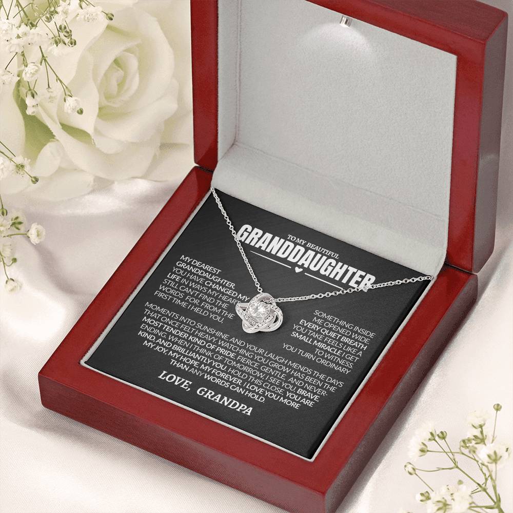 Necklace with a sentimental message card in a red box, surrounded by white flowers.