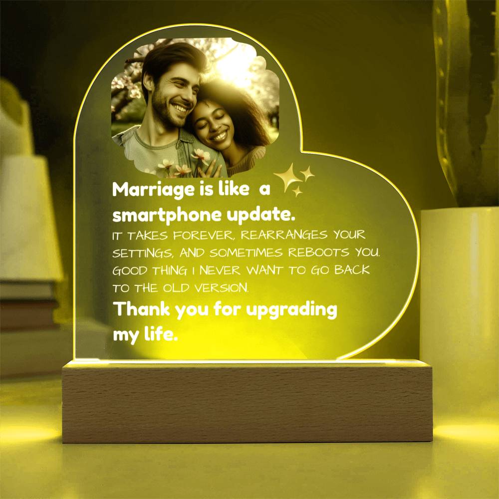 Heart-shaped LED light with a couple's photo and humorous quote on a wooden base.