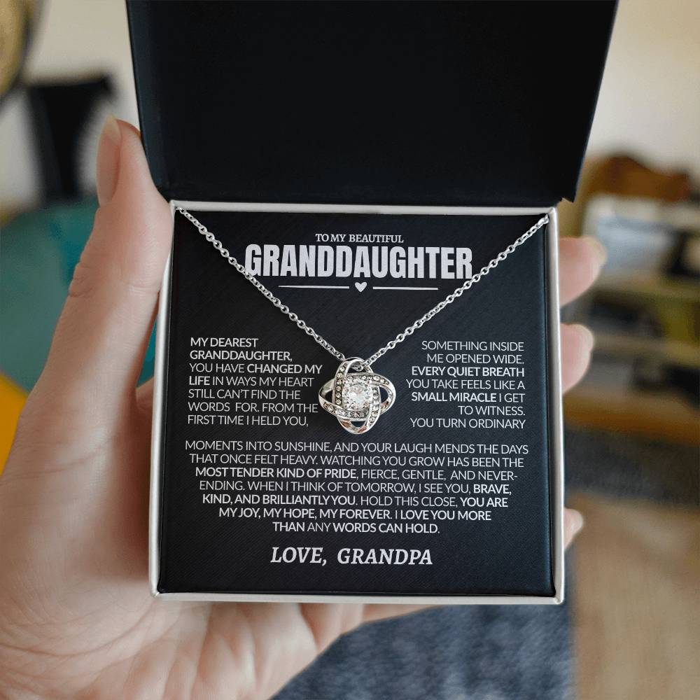 Necklace in a box with a sentimental message to granddaughter, held by a hand.