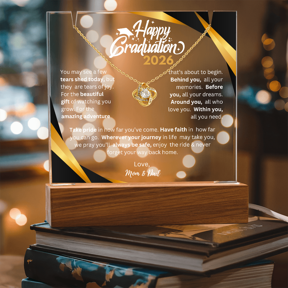 Graduate’s desk with a glowing personalized acrylic plaque on a wooden LED base and a Love Knot Necklace — perfect dorm or display piece.