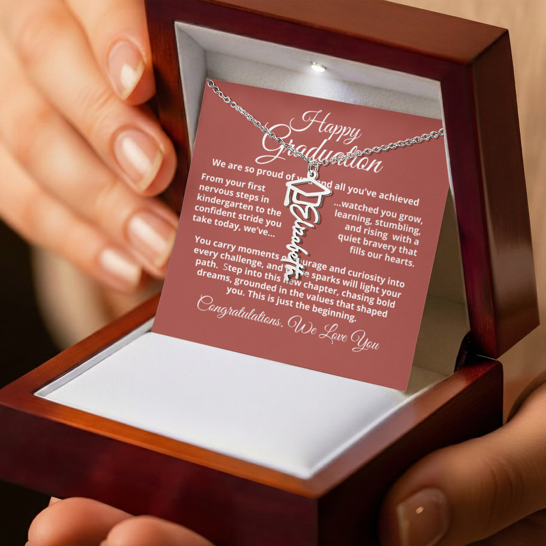 Custom Graduation Cap Name Necklace featuring a signature script nameplate and tiny graduation cap accent; choose polished stainless steel or 18K yellow gold finish; hangs on an adjustable 18–20" cable chain — a meaningful keepsake gift.