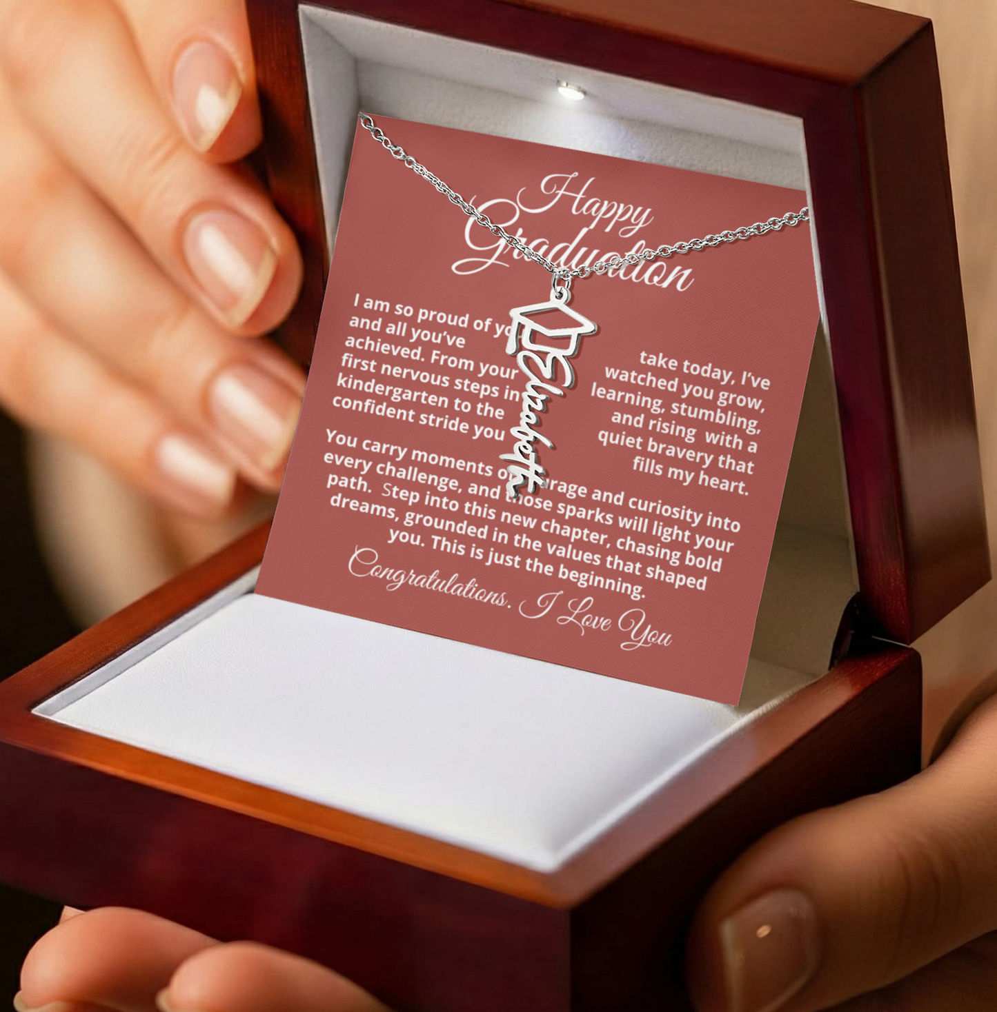 Graduation necklace with card in wooden box held by hands