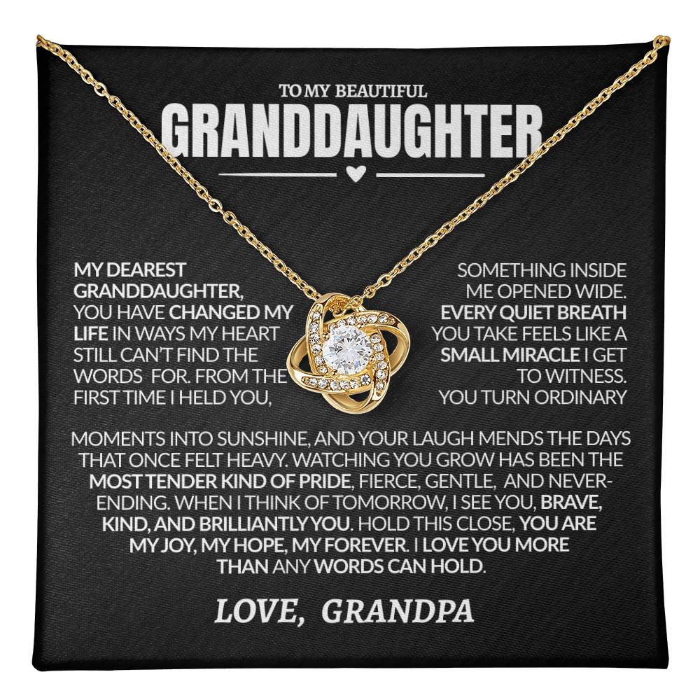 Gold necklace with heart pendant on a black card with heartfelt message to granddaughter
